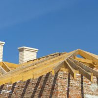 Roofing Construction. Wooden Roof Frame, White Chimneys and Yellow Brick House Construction